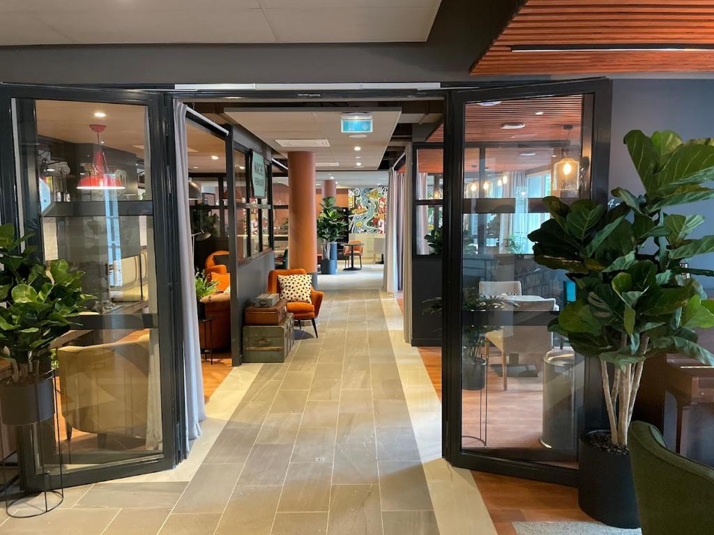 a store hallway with glass doors and potted plants at CAZAM Paris Saint Ouen in Saint-Ouen