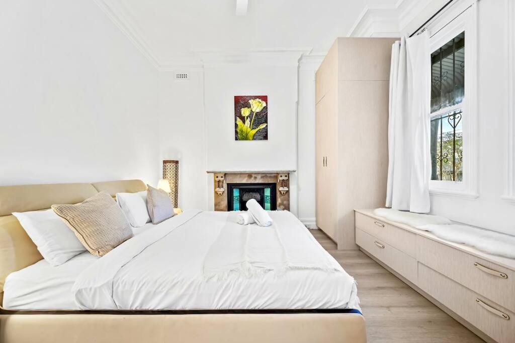 a white bedroom with a large bed and a fireplace at Modern 4B2B house@Glebe in Sydney