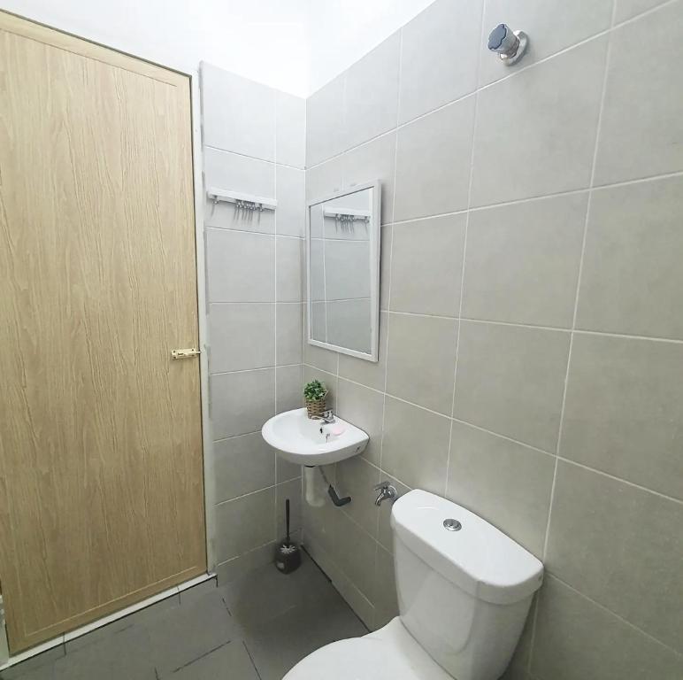 La salle de bains blanche est pourvue de toilettes et d'un lavabo. dans l'établissement Sakura Thirty Guest House , Homestay Seri Iskandar, à Seri Iskandar