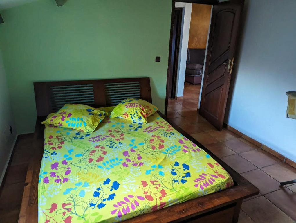 uma cama com um edredão colorido e almofadas em Appartement d'une chambre avec jardin clos et wifi a Le moule a 1 km de la plage em Le Moule