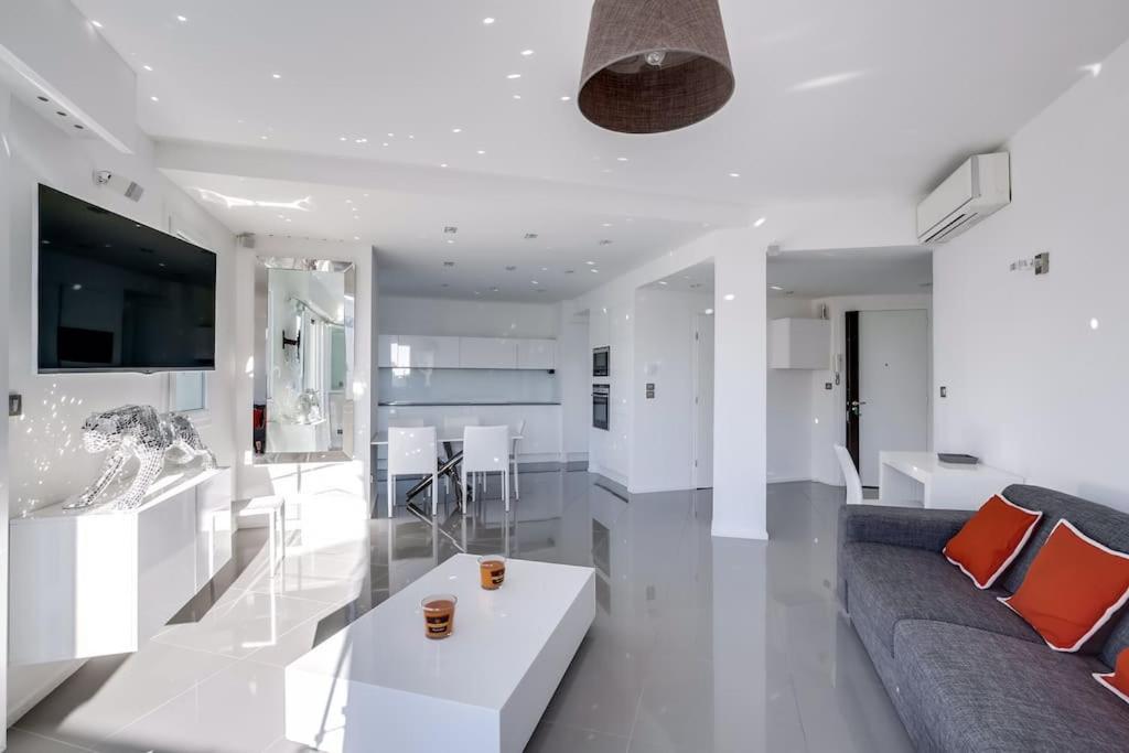 ein weißes Wohnzimmer mit einem Sofa und einem Tisch in der Unterkunft Luxueux appartement à 50 m de la Croisette in Cannes