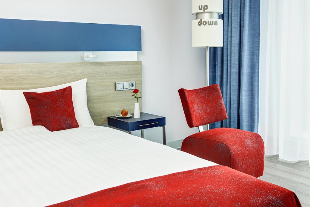 a bedroom with a bed and a red chair at IntercityHotel Enschede in Enschede