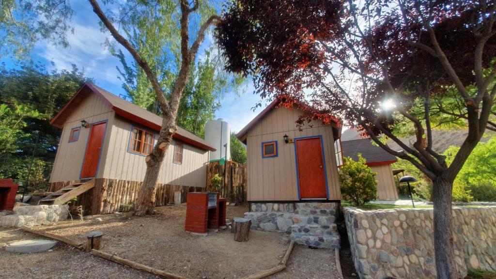 a small house with a red door in a yard at Cabañas Las Gredas SPA Pisco Elqui in Pisco Elqui