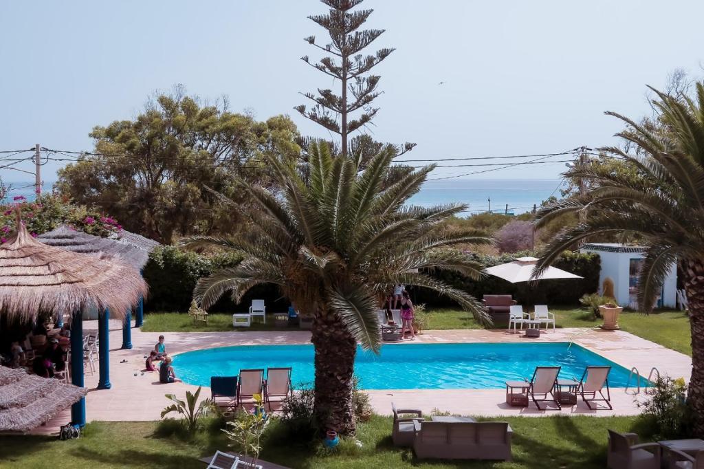 vistas a una piscina con palmeras y sillas en Dar Oguz en Ḩammām al Ghazzāz