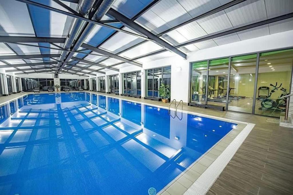 a large swimming pool with blue water in a building at Crystal Wood Apartment 213 in Bakuriani