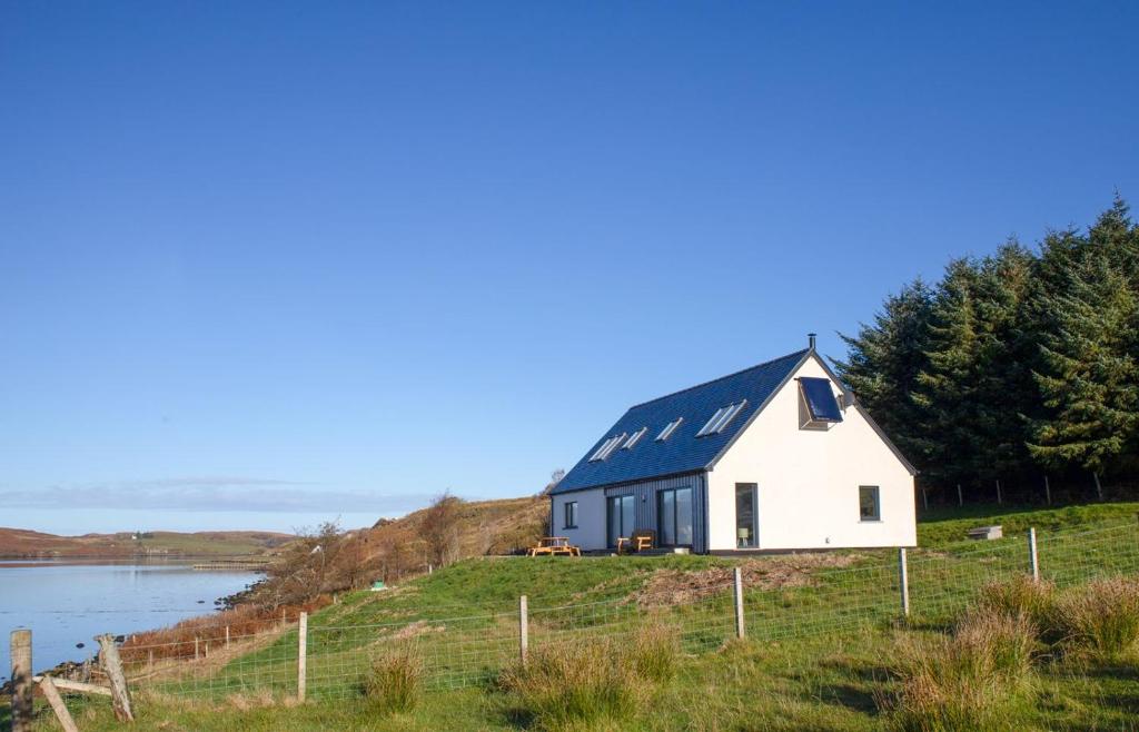 a house on a hill next to a body of water at Daisy Cottage in Eyre