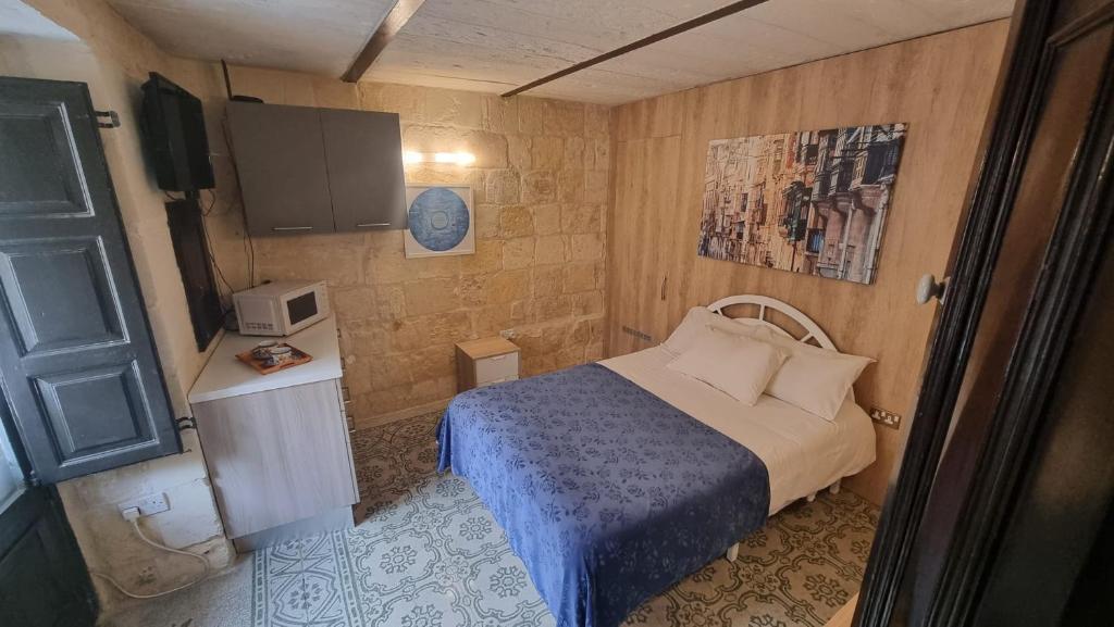 a small bedroom with a bed and a tv at Servants' Quarters Studio Apartment in Valletta