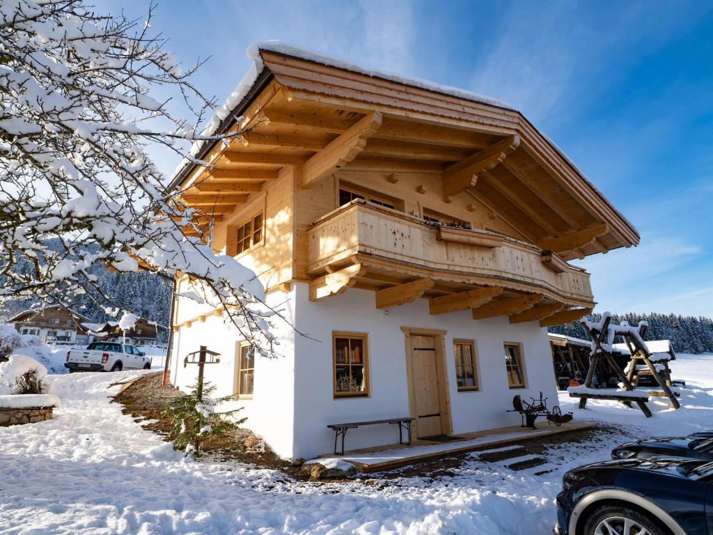 a small house with a balcony in the snow at Ferienhaus Weberhof in Hopfgarten im Brixental
