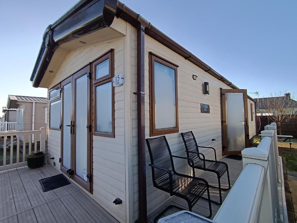 uma pequena casa com duas cadeiras num deque em Seascape Camber Sands Holiday Let em Camber