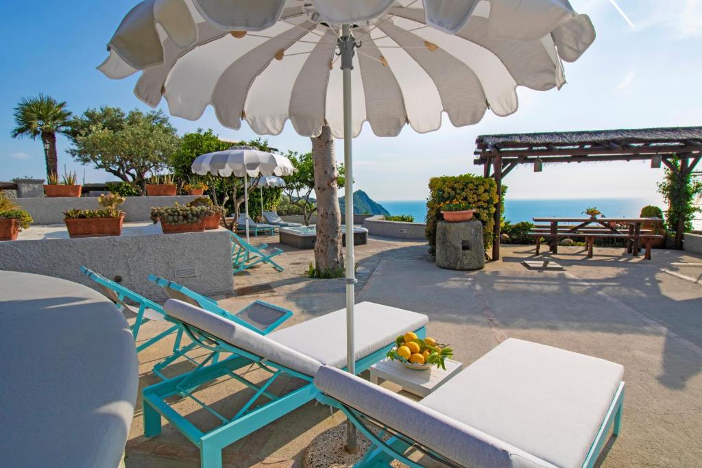 stół i krzesła pod parasolem na plaży w obiekcie Villa Titina - Sunset Apartments w mieście Ischia
