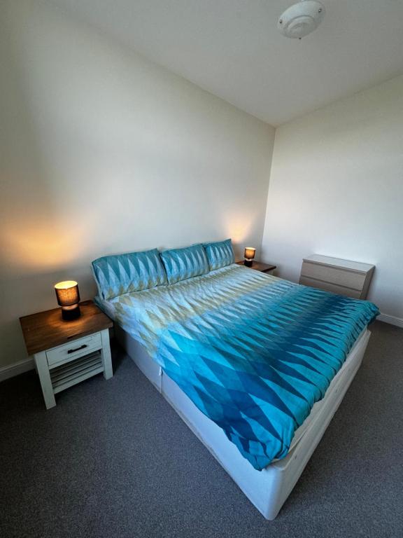 a bedroom with a bed with blue sheets and a table at Doc Fictoria in Caernarfon