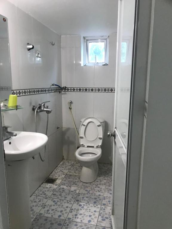 a white bathroom with a toilet and a sink at Hotel Thuý đông in Sóc Sơn