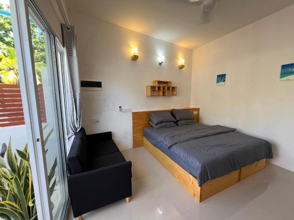 een kleine slaapkamer met een bed en een bank bij The Wave Dhigurah in Dhigurah