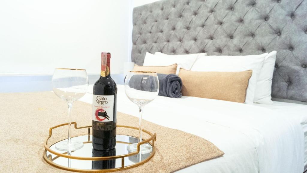 a bottle of wine and two glasses on a bed at Apto nuevo a 5 min del Movistar Arena in Bogotá