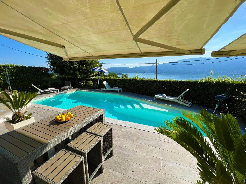 a swimming pool with a table and chairs and an umbrella at Pellegrini Boutique Villa Lake View in Verbania