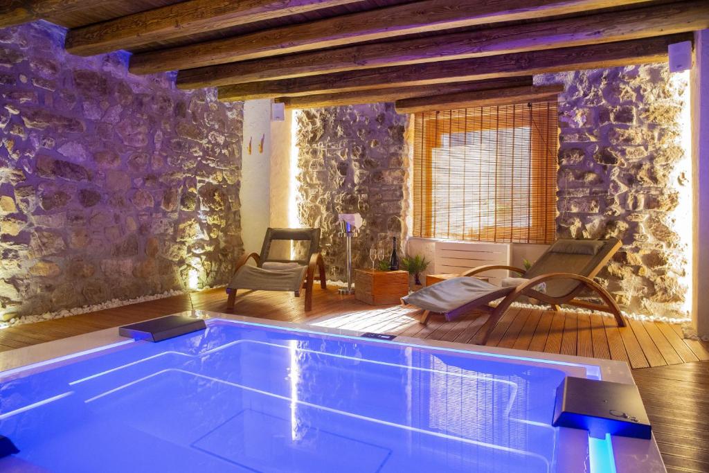 una piscina en una habitación con una pared de piedra en PORTA SOPRANA luxury guest House & spa, en Sclafani