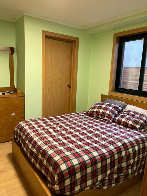 een slaapkamer met een bed met een geruite deken en een raam bij Mini Apartamento de 30 mts en Chaves in Chaves