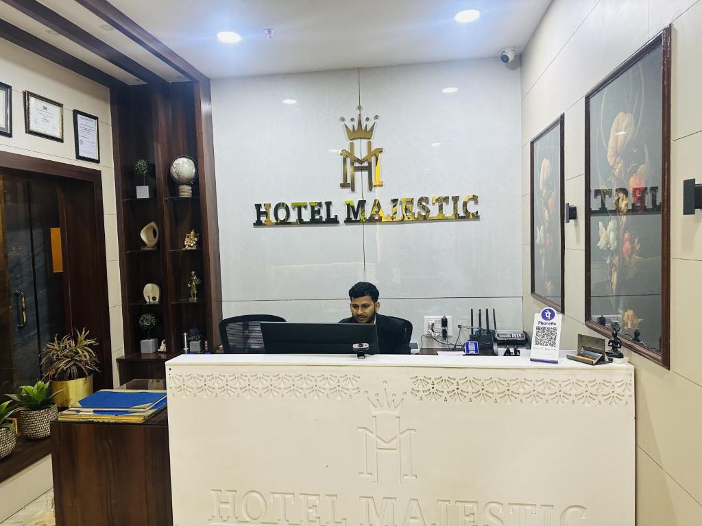 un uomo seduto alla reception di un hotel di Hotel Majestic a Calcutta