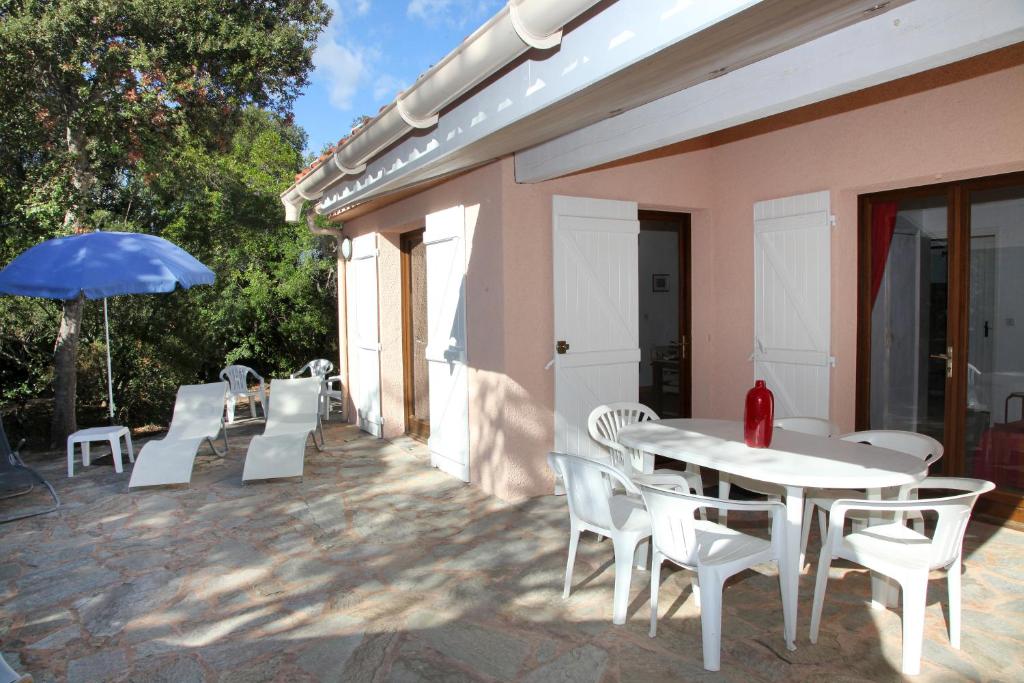 un patio avec une table, des chaises et un parasol dans l'établissement Villa Tizzano, Santa Giulia, à Porto-Vecchio