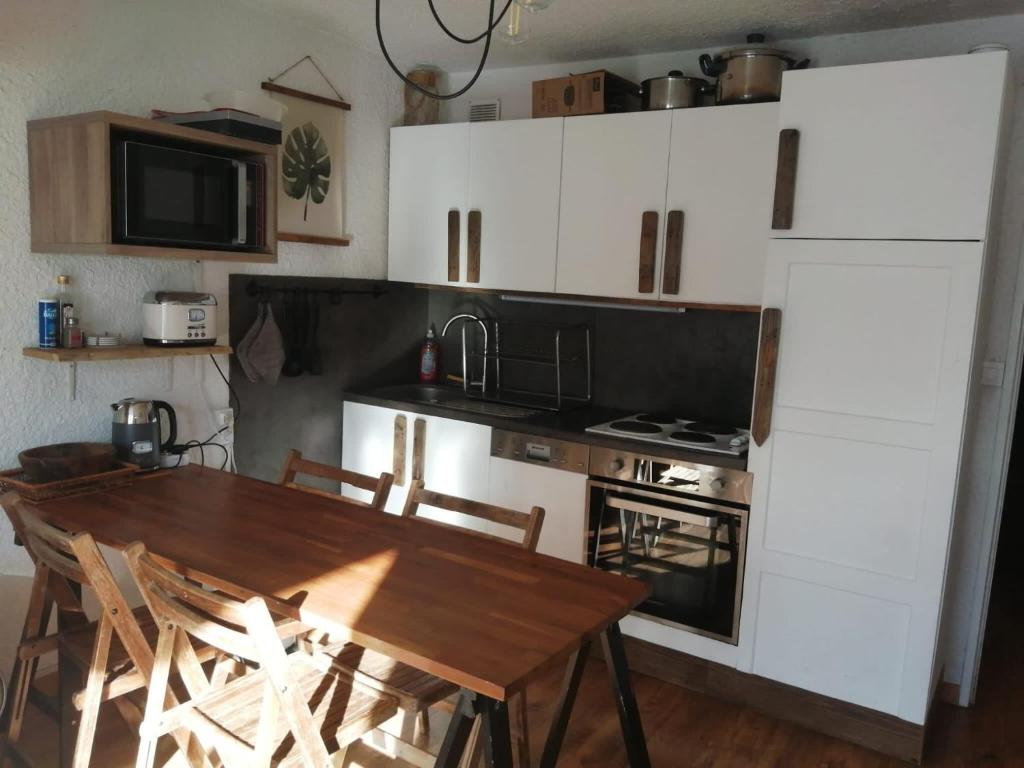 cocina con mesa de madera y cocina con fogones en Meijotel 28 - Appt idealement situe 4 pers en Les Deux Alpes