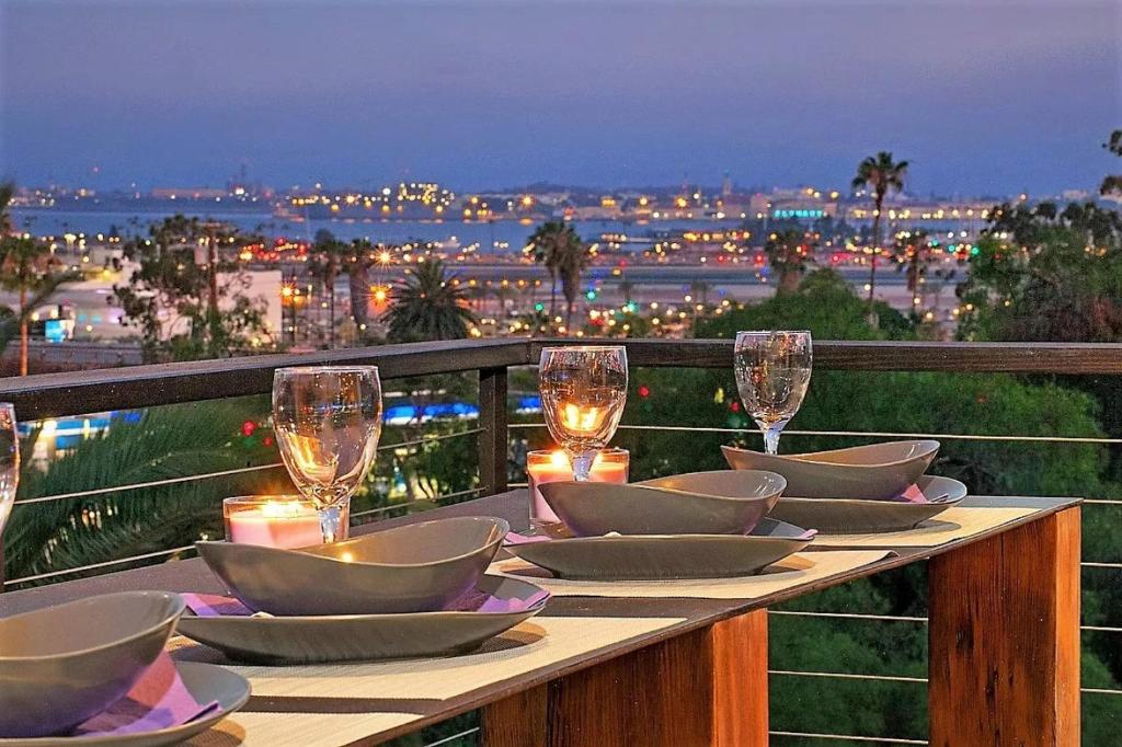 una mesa con vasos, platos y velas en el balcón en New! Luxury 5BR, W/Arcade, Sauna, Views, Fire Pit!, en San Diego