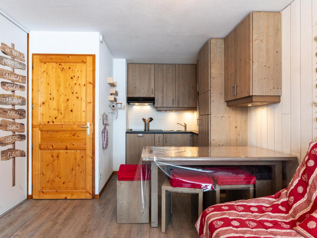 a kitchen with wooden cabinets and a table with red chairs at Les Sitelles - 12 - Appt vue montagne - 6 pers in Morillon