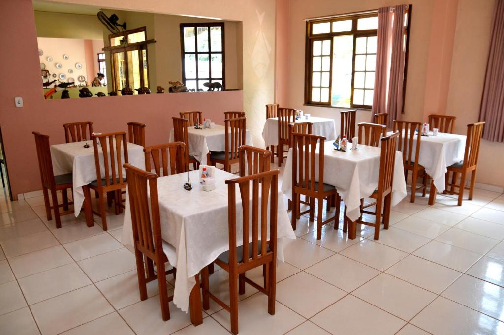 una sala da pranzo con tavoli bianchi e sedie in legno di Pousada Cabocla ad Alter do Chão