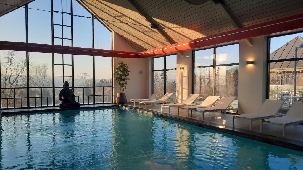 a woman sitting in a pool with chairs and windows at Azur en Ardenne in Durbuy