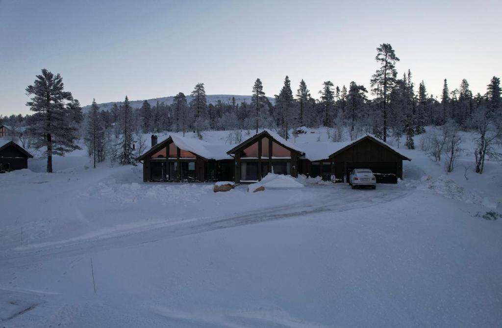 dom na śniegu z samochodem zaparkowanym przed budynkiem w obiekcie Luxurious Mountain Lodge w mieście Ljørdal