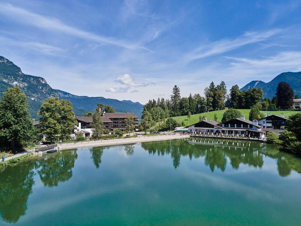 ein großer See mit Häusern und Bergen im Hintergrund in der Unterkunft Riessersee Hotel in Garmisch-Partenkirchen