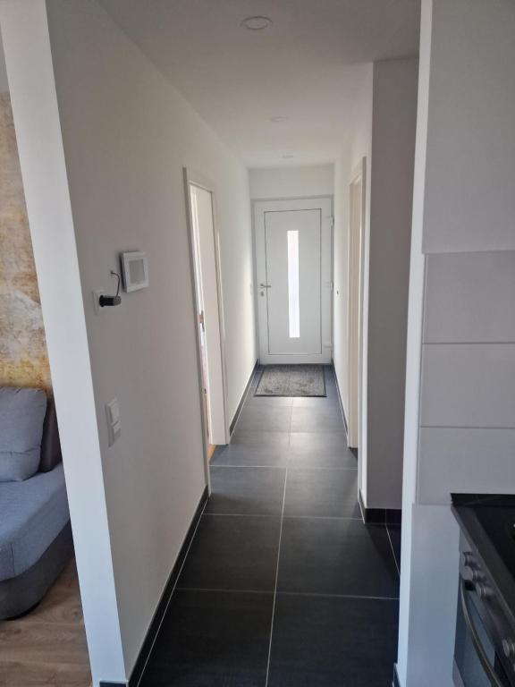 a hallway with white walls and black tile floors at Ferienwohnung Tihana in Trossingen