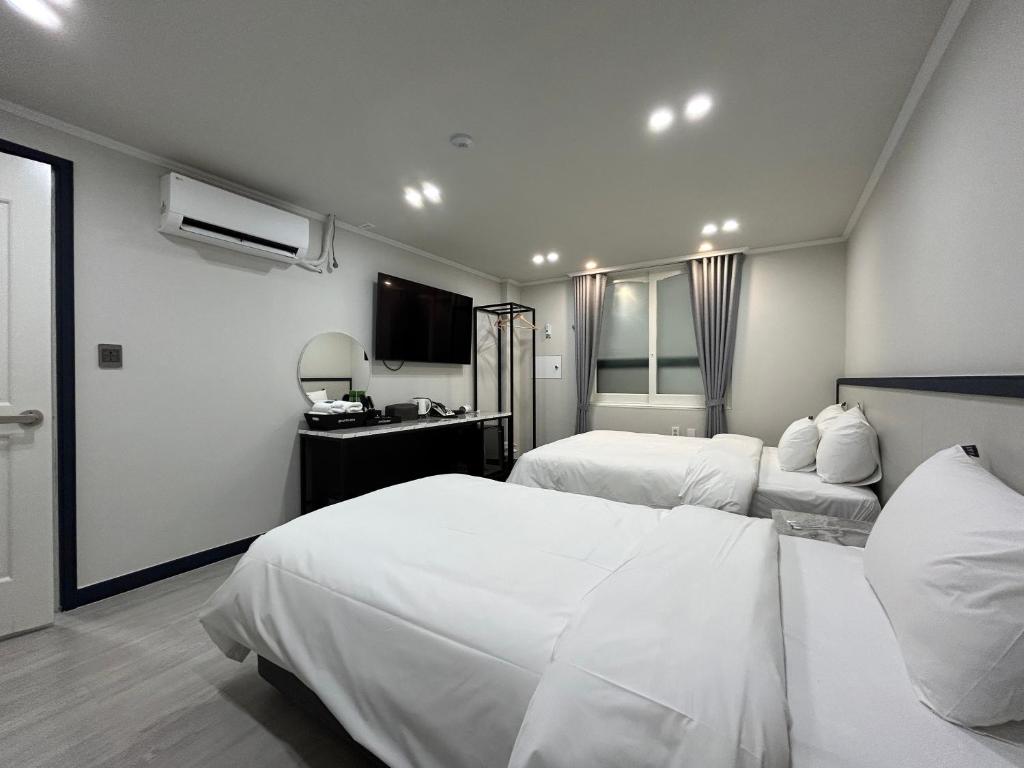 a hotel room with two beds and a television at Hotel Bom in Mokpo