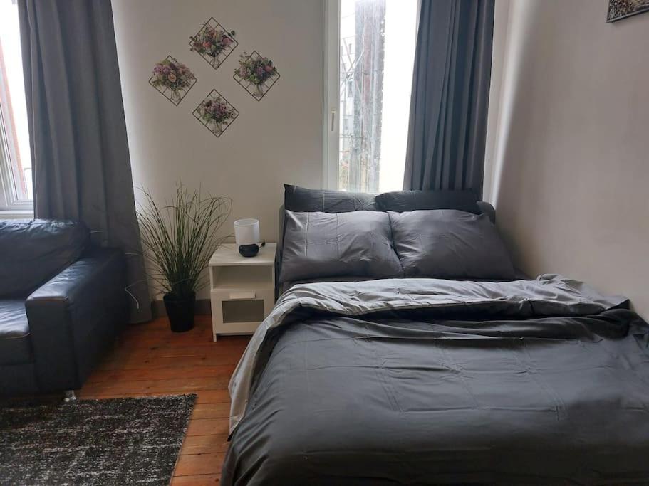 um quarto com uma cama, um sofá e janelas em Cosy Studio em Bruxelas