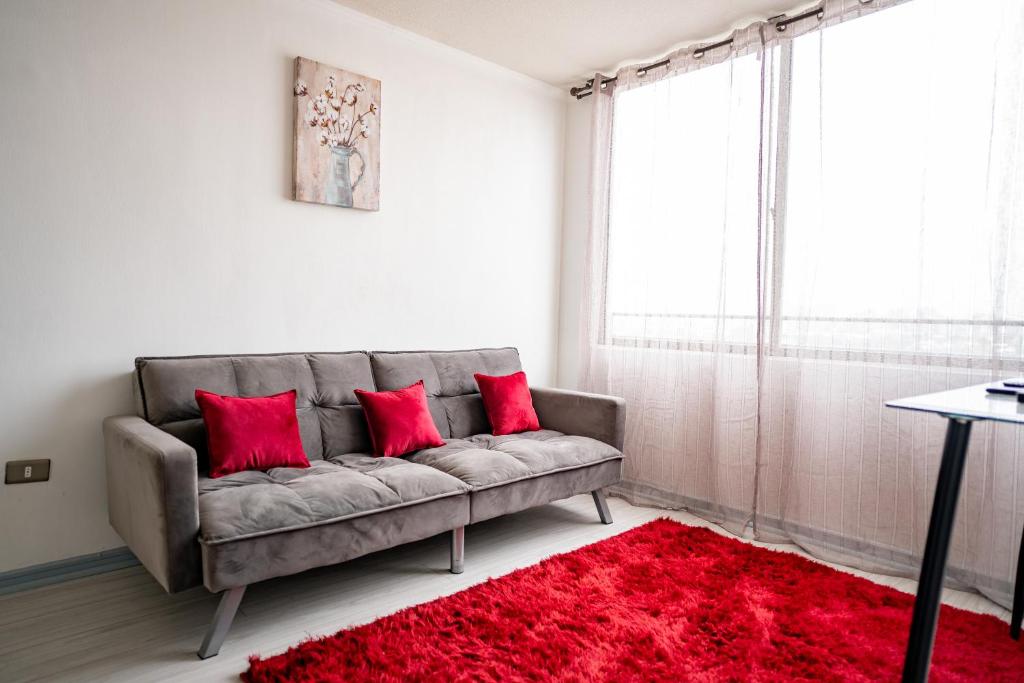 a living room with a gray couch with red pillows at Bonito departamento a pasos del Movistar Arena. in Santiago