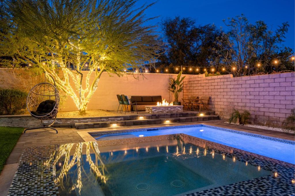 a swimming pool with lights in a backyard at night at Sueno Terra Lago Luxury Pool House in Indio