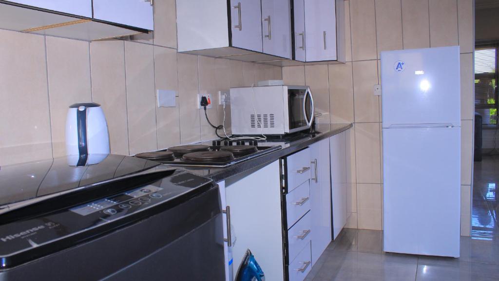 a kitchen with a stove and a white refrigerator at Serene Cottage in Francistown