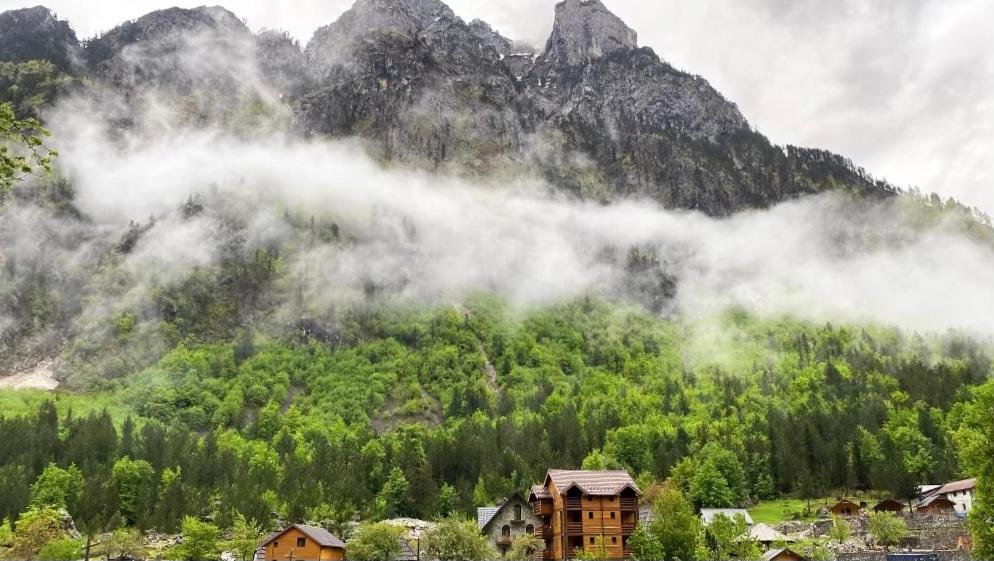 a mountain obscured by clouds with houses and trees at Guesthouse Gezim Selimaj in Valbonë