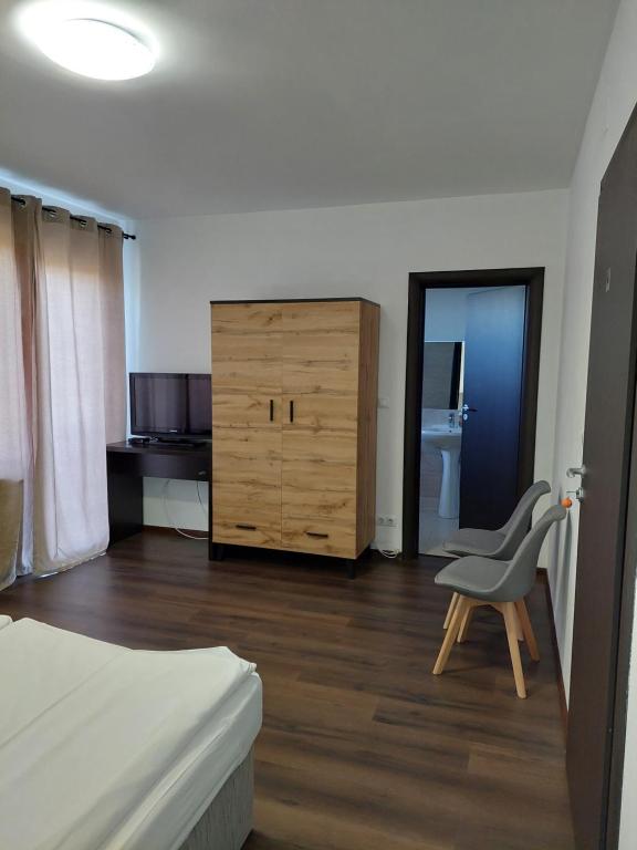 1 dormitorio con cama, silla y vestidor en Pensiunea Grandor en Păltiniş