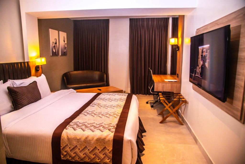 a hotel room with a bed and a desk and a television at Golden Tulip Lekki in Lekki