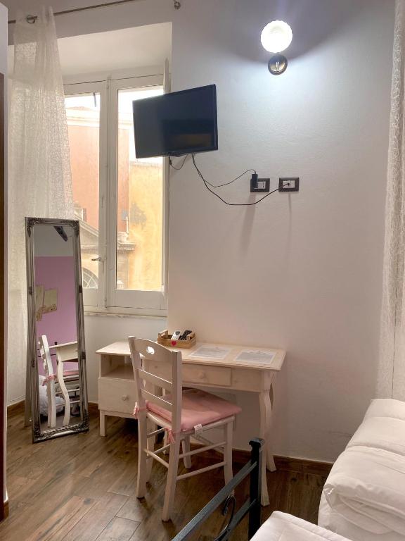 a room with a desk and a tv on the wall at Dani's House - affittacamere nel cuore di Cagliari in Cagliari