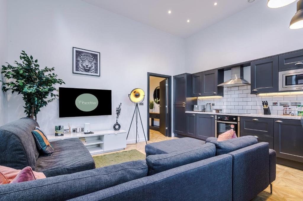 a living room with two blue couches and a kitchen at Gorgeous Central Flat - Perfect Corporate Stay by PureStay Short Lets in Leeds