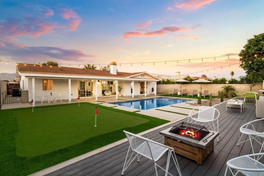a backyard with a pool and a lawn with chairs and a fire pit at Mid Century Modern Pool Paradise with Putting Green in Bermuda Dunes
