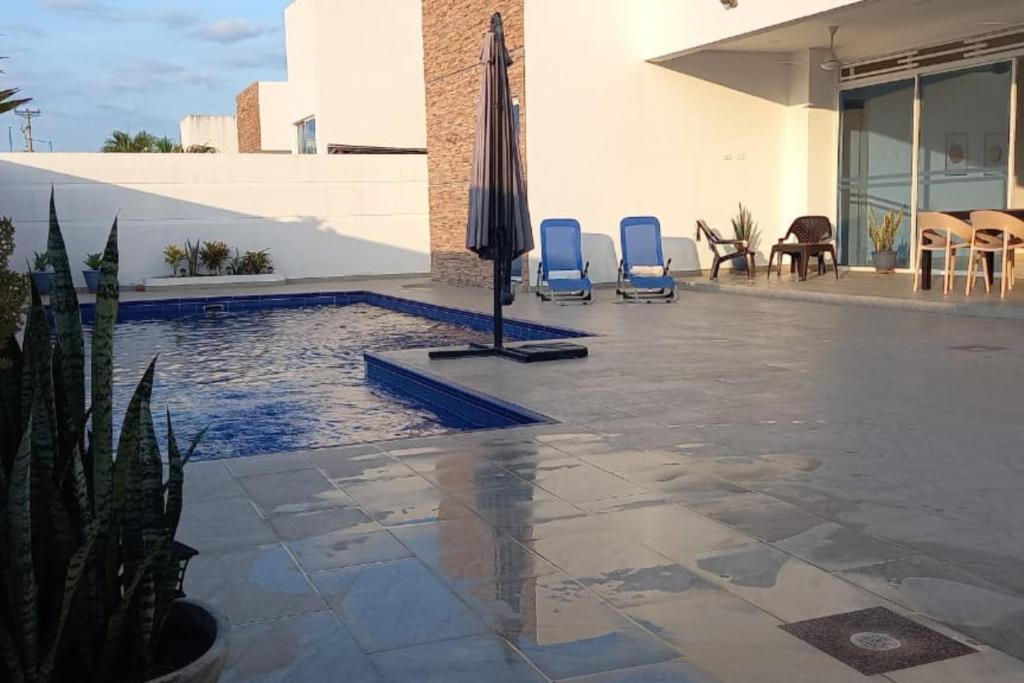 a swimming pool with two blue chairs and an umbrella at Casa Quinta Moderna Piscina Privada En via Girardot in Girardot