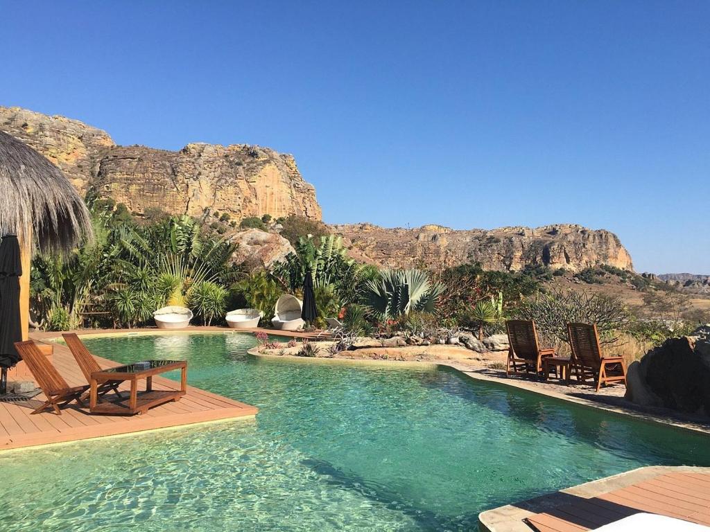 a swimming pool with chairs and mountains in the background at Satrana Lodge in Ranohira