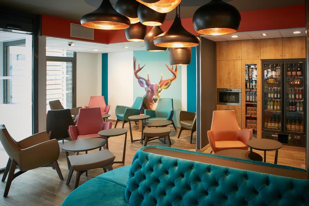 - un bar avec des chaises colorées et une tête de cerf sur le mur dans l'établissement Kyriad Pontarlier, à Pontarlier