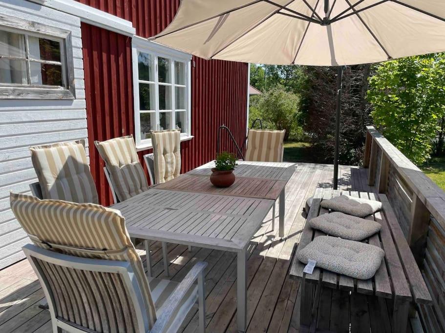 ベステルビークにあるMysigt hus för 2 familjerの木製テーブル、椅子、パラソル付きのデッキ