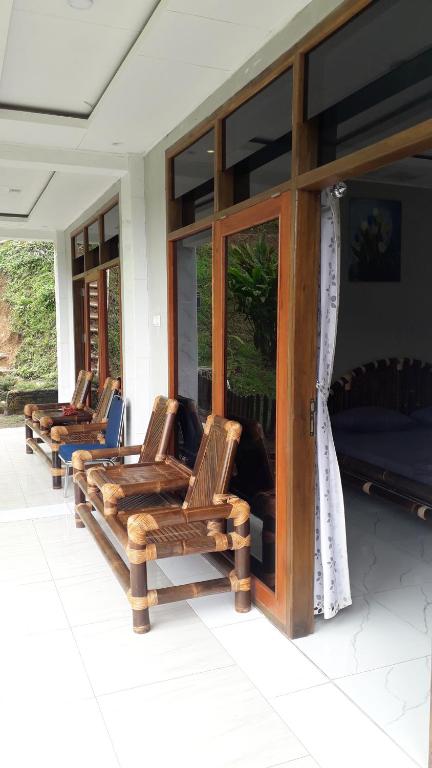 uma fila de cadeiras sentadas num alpendre em Villa Situ Jampang Campsite em Megamendung