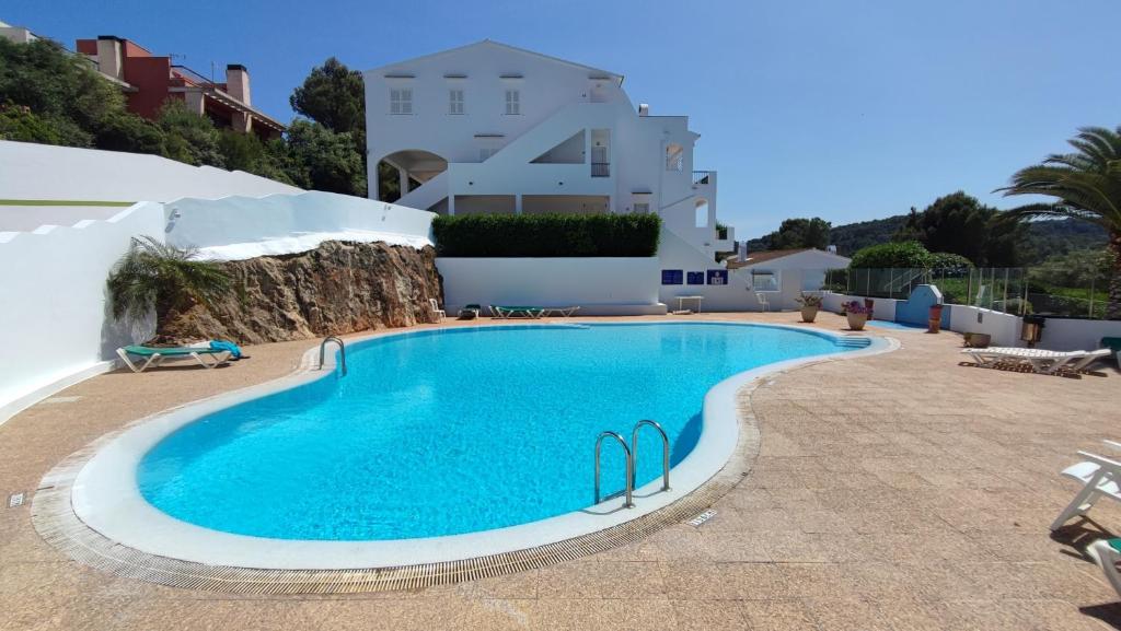 a large swimming pool in front of a white building at Apartamento en el campo de golf Son Parc, Menorca in Son Parc