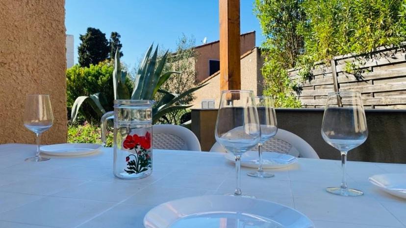 une table avec trois verres à vin et un vase avec des fleurs dans l'établissement Maison Solane 1 Lumio, à Lumio