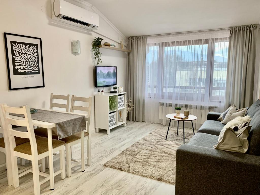 uma sala de estar com um sofá, uma mesa e uma televisão em Snowflake home - Private apartment em Bansko